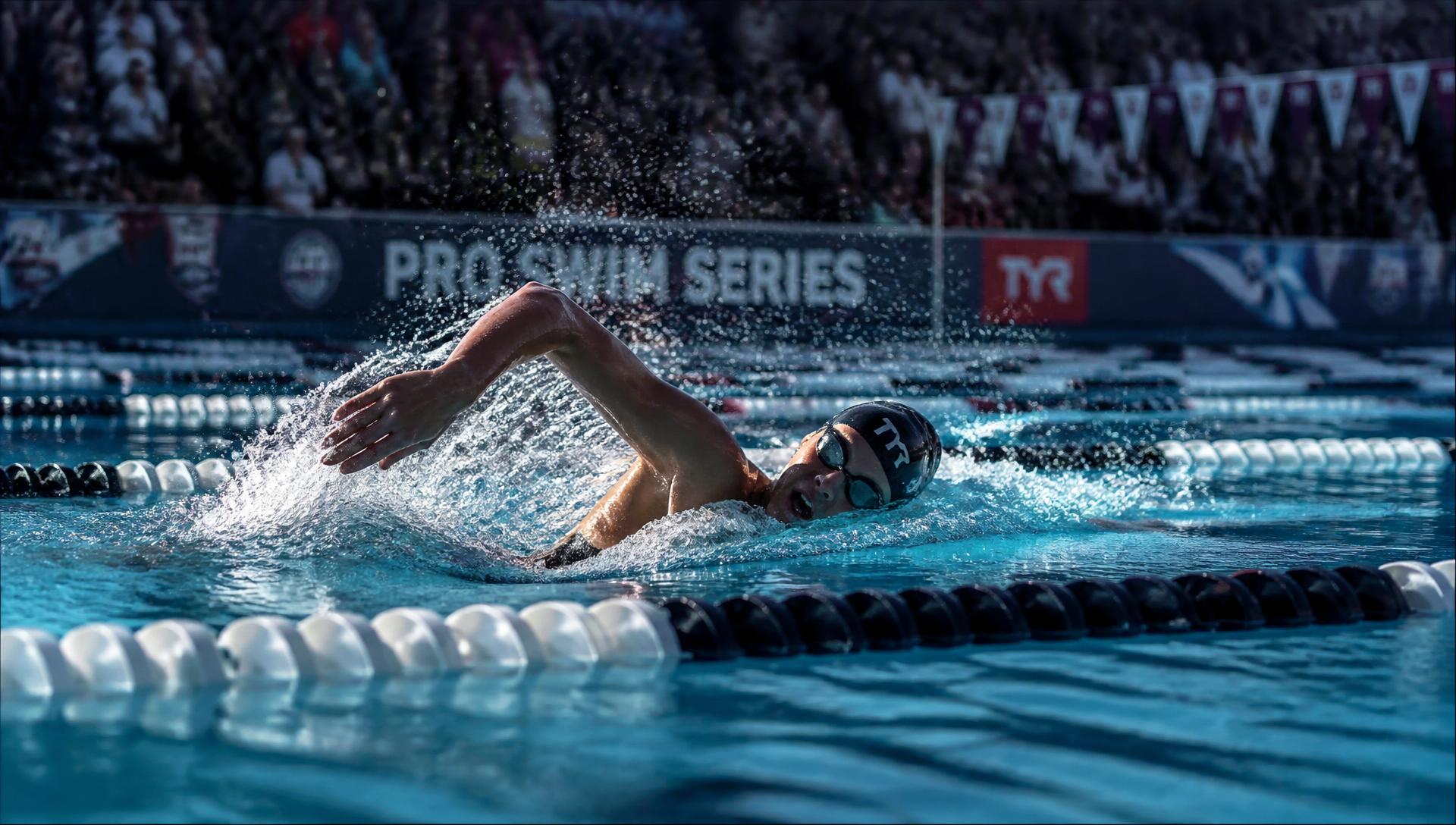 Swimmer racing freestyle at an indoor competition pool